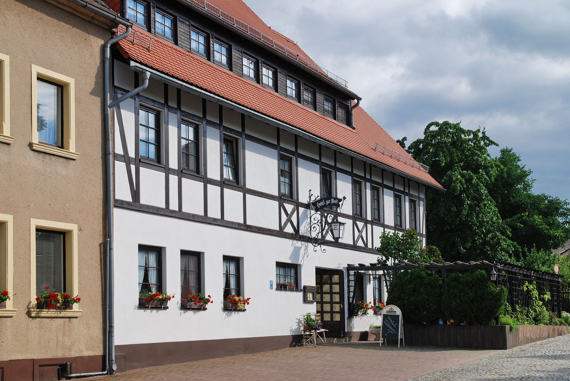 Ein traditionelles Gasthaus mit roten Dachziegeln und Fachwerkfassade in Hochkirch, umgeben von grünen Bäumen.