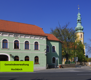 Außenansicht der Gemeindeverwaltung Hochkirch, daneben die historische Kirche, Zentrum des Gemeindelebens.