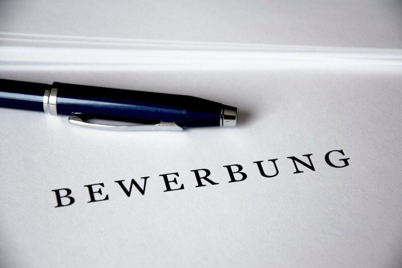 Ein Dokument mit dem Wort "BEWERBUNG" und einem Stift, symbolisiert Stellenangebote der Gemeinde Hochkirch.